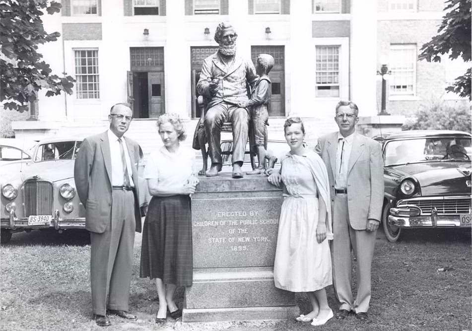 Black & white photograph of four people in front of the Sheldon statue.  Written on the back, "Left to right, Dr. Brown, Mrs. Frances Inman Davis, Daughter Carol & Husband Joseph Davis.
 - Page 1
