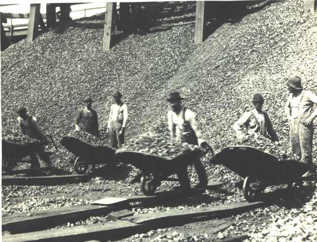 Men loading coal with wheel ba