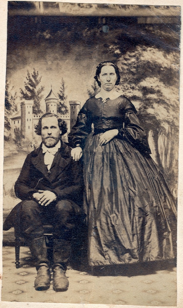 Peter Simpkins and Lucy Simpkins.  Black & white formal portrait.  Lucy Simpkins is standing with her hand on Peter's shoulder.